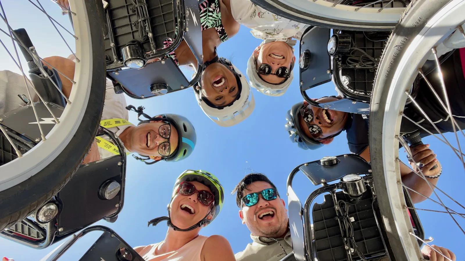 group of happy people looking over their bike share handle bars smiling at the camera