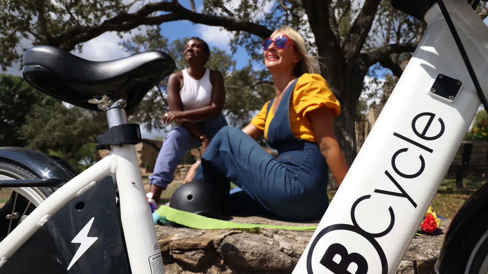 two riders taking a break to enjoy the sunshine from riding their BCycle bike
