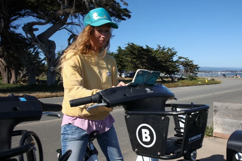 Woman using her smart phone to check out a bike share bicycle